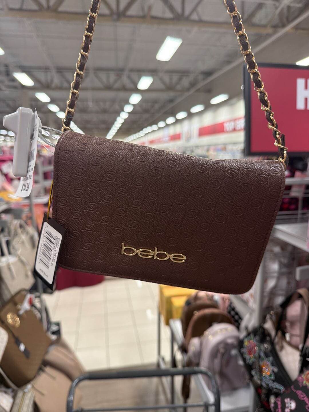 Bolso bebe café rectangular colgado en la tienda, con etiqueta y sensor antirrobo — la primera foto de un artículo en EvaTeLoCompra